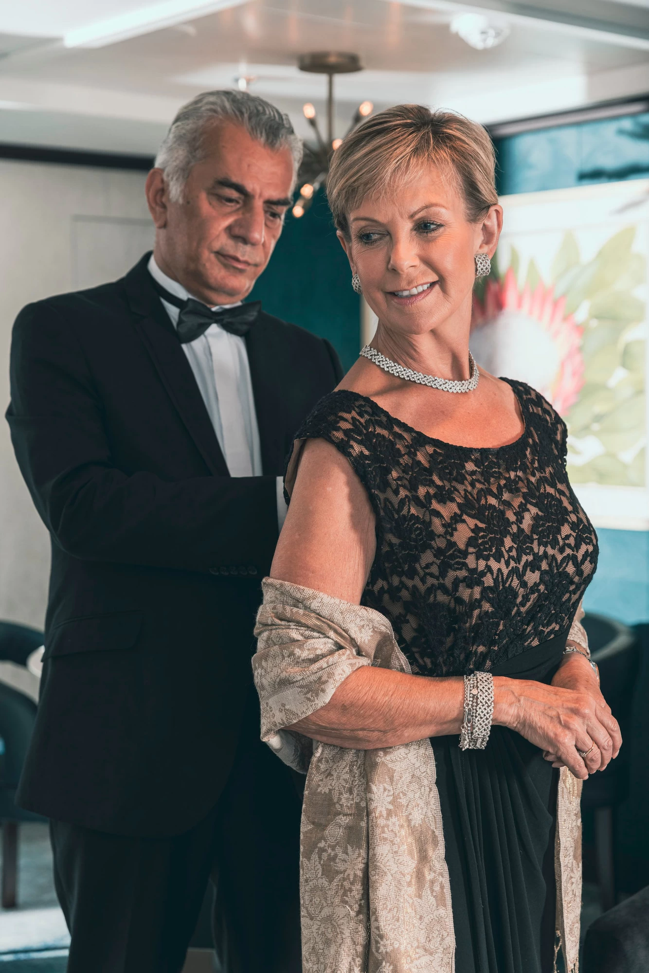 Saga cruise evening photography — couple in black-tie attire dressing for a formal night, woman in a black lace gown