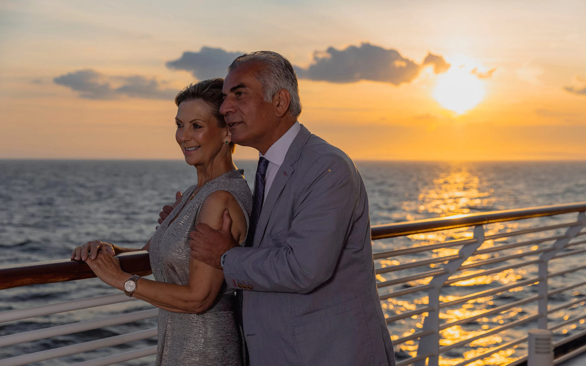 Saga cruise photography — couple watching a golden sunset from the ship’s open deck railing