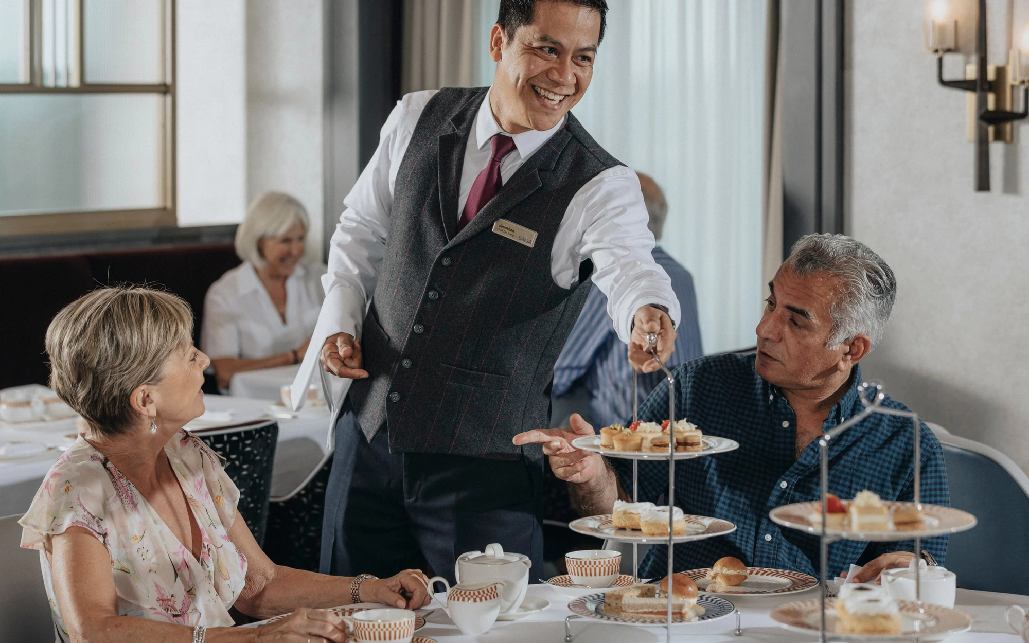 Saga cruise dining photography — afternoon tea service with a tiered cake stand presented to a couple